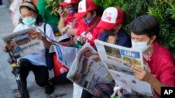 Women read newspapers showing a headline story on Ferdinand "Bongbong" Marcos Jr. and running mate Davao City Mayor Sara Duterte as they celebrate outside their headquarters in Mandaluyong, Philippines, May 10, 2022.