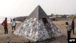 Des hommes regardent une installation artistique de l'artiste sénégalais Yakhya Ba, le long de la promenade maritime de Dakar, le 11 mai 2022.