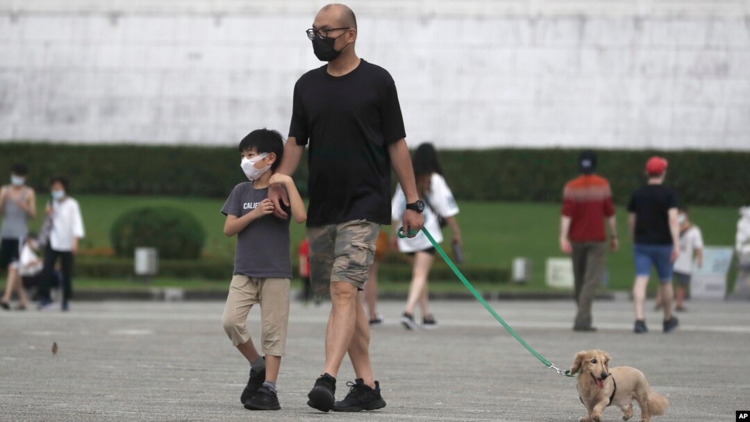 台北市民戴著口罩遛狗散步。 （2022年4月27日）