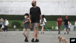 台北市民戴着口罩遛狗散步。（2022年4月27日）