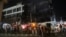 Rescue workers and onlookers stand as crews douse a fire that broke out at a commercial building in Delhi's western suburb of Mundka, May 13, 2022.