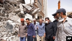 In this photo released by official website of the office of Iranian Senior Vice-President, on May 27, 2022, Vice-President Mohammad Mokhber, second right, visits the site of a tower at under construction 10-story Metropol Building which collapsed in the s