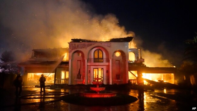 Firefighters work to put out a structure burning during a wildfire May 11, 2022, in Laguna Niguel, Calif.