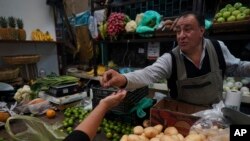 A vegetable vendor gives change to a customer at Medellin Market in Mexico City, May 9, 2022.