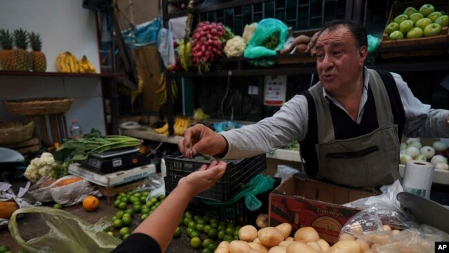 A vegetable vendor gives change to a customer at Medellin Market in Mexico City, May 9, 2022.