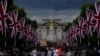 Orang-orang berdiri di The Mall melihat ke arah Istana Buckingham dan patung Queen Victoria Memorial di London, 31 Mei 2022. (Foto: AP)