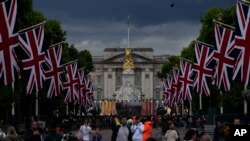 Orang-orang berdiri di The Mall melihat ke arah Istana Buckingham dan patung Queen Victoria Memorial di London, 31 Mei 2022. (Foto: AP)