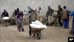 FILE: People receive food rations distributed by a South Korea humanitarian aid group, in Kabul, Afghanistan, May 10, 2022.