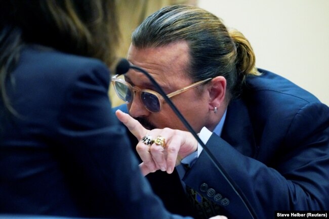 Aktor Johnny Depp berbicara dengan pengacaranya selama kasus pencemaran nama baik terhadap mantan istrinya, aktor Amber Heard, di ruang sidang di Fairfax County Circuit Courthouse di Fairfax, AS, 23 Mei 2022. (Foto: Steve Helber via REUTERS)