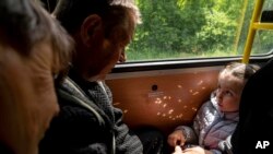 Una niña con sus abuelos de Lyman viajan en el autobús durante la evacuación cerca de Lyman, Ucrania, el 11 de mayo de 2022.
