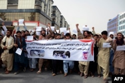 FILE - Protesters shout slogans and hold a banner during a demonstration against the Pakistani airstrikes, at the Martyrs' Square in Kandahar, April 18, 2022.