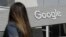 FILE - A woman walks below a Google sign on the campus in Mountain View, Calif., on Sept. 24, 2019.