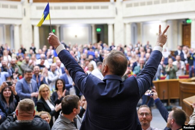 안제이 두다(가운데 뒷모습) 폴란드 대통령이 22일 우크라이나 의회 연단에서 우크라이나 국기와 함께 손가락으로 승리의 'V' 표시를 들어보이자 의원들이 박수하고 있다.