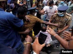 Police officers try to protect a supporter of Sri Lanka's ruling party during a clash with anti-government demonstrators, in front of the Prime Minister's official residence, amid the country's economic crisis, in Colombo, Sri Lanka, May 9, 2022.