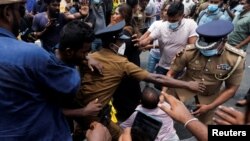 Police officers try to protect a supporter of Sri Lanka's ruling party during a clash with anti-government demonstrators, in front of the Prime Minister's official residence, amid the country's economic crisis, in Colombo, Sri Lanka, May 9, 2022. 