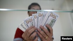 FILE: Bank staff shows U.S. hundred dollars bills at AYA Bank's money changer in Yangon July 17, 2015. REUTERS/Soe Zeya Tun