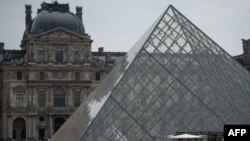 FILE - Visitors queue in front of the Pyramid to enter the Louvre Museum, in Paris on April 29, 2022.