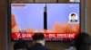 People watch a television screen showing a news broadcast with file footage of a North Korean missile test, at a railway station in Seoul on May 25, 2022.