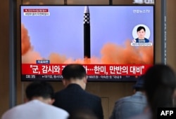 FILE - People watch a television screen showing a news broadcast with file footage of a North Korean missile test, at a railway station in Seoul, May 25, 2022.
