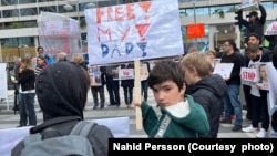 پسر احمدرضا جلالی در تجمع اعتراضی در استکهلم با پلاکاری که می‌گوید: پدر من را آزاد کنید