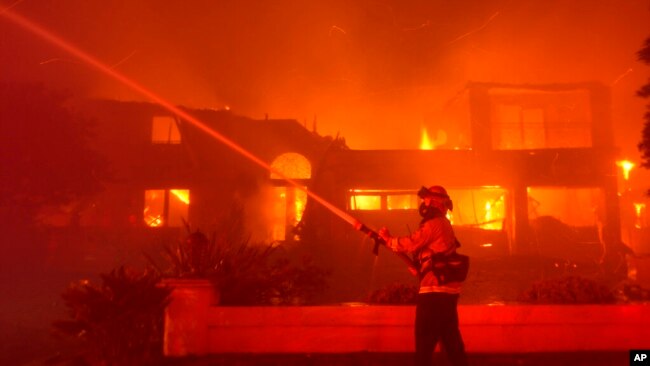 A firefighter works to put out a building burning during a wildfire May 11, 2022, in Laguna Niguel, Calif.