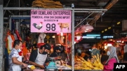 FILE - A customer waits to buy chicken meat at a wet market in Kuala Lumpur on September 1, 2021. (Photo by Mohd RASFAN / AFP)