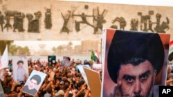 Followers of Shiite cleric Muqtada al-Sadr hold posters with his photo as they celebrate the passing of a law criminalizing the normalization of ties with Israel, in Tahrir Square, Baghdad, Iraq, May 26, 2022.