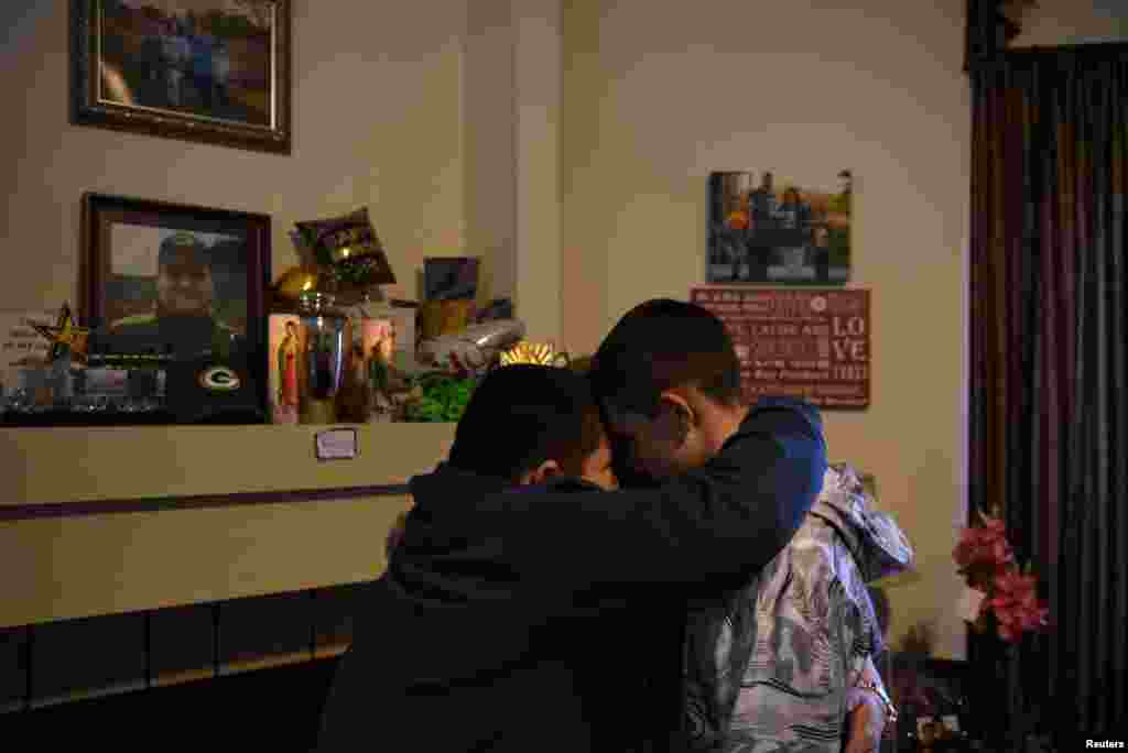 Aidan Garza, 12, (L) Julius Garza, 14, (R) and Margaret Garza (C) pray together next to their father’s urn, which they call 'the vessel,' in Converse, Texas, March 30, 2022. No government program at any level is tracking American families such as Aidan and his big brother Julius' in which at least one of a child's primary caregivers has died of COVID, but researchers' estimates put the number at over 181,000. Deep racial disparities among kids who lost at least one parent or caregiver to COVID reflect the course of a disease that has illuminated inequities in areas such as healthcare in the United States. Native American children, for instance, are four times as likely to have lost a parent to COVID than white kids.
