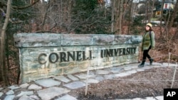 Una mujer camina junto a un anuncio de la Universidad de Cornell en el campus de esta escuela de la Ivy League en Ithaca, Nueva York, el 14 de enero de 2022. 