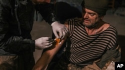 In this photo provided by Azov Special Forces Regiment of the Ukrainian National Guard Press Office, an Azov Special Forces Regiment's serviceman receives treatment inside the Azovstal steel plant in Mariupol, Ukraine, May 10, 2022.
