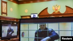 Russian opposition leader Alexei Navalny is seen on screens via a video link from the IK-2 corrective penal colony in Pokrov during a court hearing to consider an appeal against his prison sentence in Moscow, May 24, 2022. 