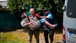 A woman is carried from her home in an evacuation by volunteers of Vostok SOS charitable organization in Bakhmut, eastern Ukraine, May 27, 2022. 