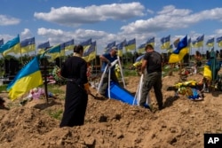Undertakers lower the coffin of Ukrainian serviceman Oleksander Matyukhin, 32, in Kharkiv, eastern Ukraine, May 23, 2022.