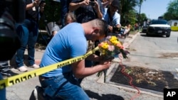 Joseph Avila, left, prays while holding flowers honoring the victims killed in Tuesday's shooting at Robb Elementary School in Uvalde, Texas, May 25, 2022.