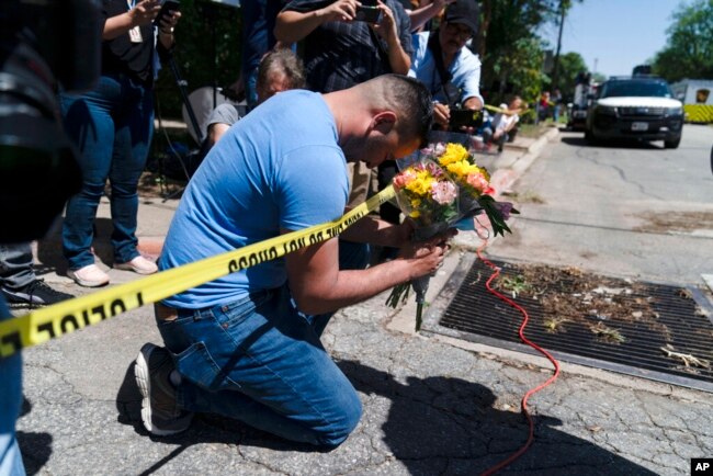 Joseph Avila, kiri, berdoa sambil memegang bunga untuk menghormati para korban yang tewas dalam penembakan di Sekolah Dasar Robb di Uvalde, Texas, 25 Mei 2022. (Foto: AP)