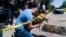 Joseph Avila, left, prays while holding flowers honoring the victims killed in Tuesday's shooting at Robb Elementary School in Uvalde, Texas, May 25, 2022.