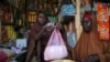 Halimo Hersi right, buys wheat flour from a shopkeeper in the Hamar-Weyne market in the capital Mogadishu, Somalia, May 26, 2022, paying about 45% more for wheat flour as Russia's war in Ukraine blocks exports from the Black Sea.