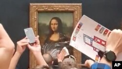 Yon gad sekirite netwaye krem gato ki kouvri vit tablo Mona Lisa a nan mize Louvre la nan vil Paris an Frans, 29 Me, 2022. 