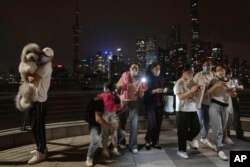 Warga berkumpul untuk berfoto saat mendekati tengah malam pada malam pencabutan lockdown COVID-19, Selasa, 31 Mei 2022, di Shanghai. (Foto: AP)