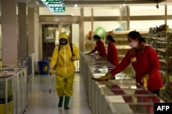 Karyawan menyemprotkan disinfektan di Pyongyang. (Foto: AFP)