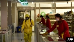 Employees spray disinfectant and wipe surfaces as part of preventative measures against the Covid-19 coronavirus at the Pyongyang Children's Department Store