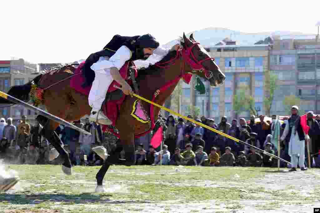 An Afghan man rushes to the target with his horse during spear racing in the sprawling Chaman-e-Huzori park in downtown Kabul, Afghanistan.