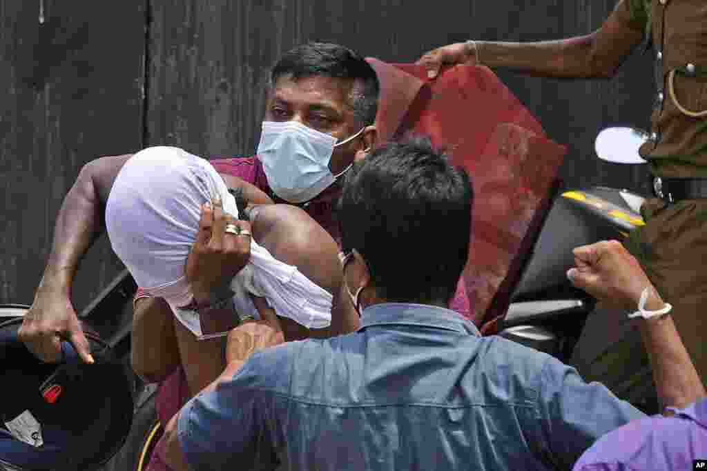 An anti-government protester, left, is hurt by Sri Lankan government supporters outside prime minister&#39;s office in Colombo, Sri Lanka.