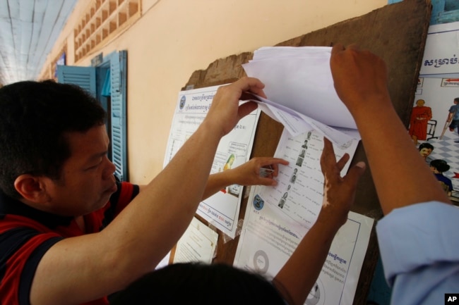 FILE - Locals look at a registration list before voting at a polling station in Phnom Penh, Cambodia, Sunday, July 29, 2018. With the main opposition silenced, Cambodians were voting in an election Sunday virtually certain to return to office Prime Minister Hun Sen and his party who have been in power for more than three decades. (AP Photo/Heng Sinith)