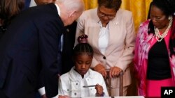 President Joe Biden gives a pen to Gianna Floyd, the daughter of George Floyd, after he signed an executive order on police accountability in the East Room of the White House, May 25, 2022, in Washington. The order came on the second anniversary of George Floyd's death at the hands of a Minneapolis police officer.