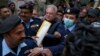 FILE - Police officers escort Pakistani journalist Mohsin Baig, center, for his court appearance, in Islamabad, Pakistan, Feb. 16, 2022. Police arrested Baig at his home on unspecified charges, his colleagues and local media said.