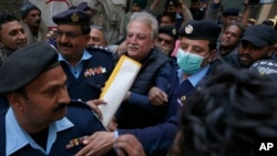 FILE - Police officers escort Pakistani journalist Mohsin Baig, center, for his court appearance, in Islamabad, Pakistan, Feb. 16, 2022. Police arrested Baig at his home on unspecified charges, his colleagues and local media said.