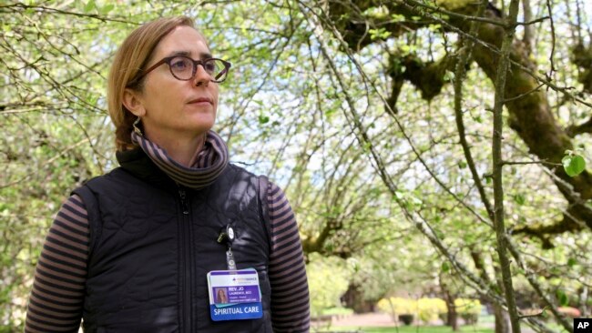 Rev. Jo Laurence, a Buddhist chaplain, poses for a photo in the garden of a memory care facility in Portland, Oregon, April 22, 2022, before visiting hospice patients to offer spiritual care.