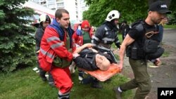 Paramedis dan pekerja darurat membawa seorang pria yang terluka dalam penembakan di Kharkiv pada 26 Mei 2022. (Foto: AFP)