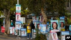 A volunteer stands amongst billboards for candidates outside a polling station in Sydney, Australia, May 9, 2022.